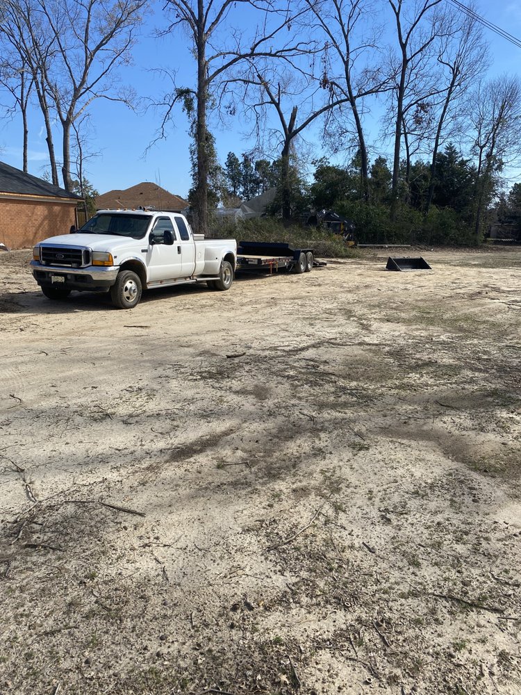 Ford dually truck and equipment trailer at a cleared lot